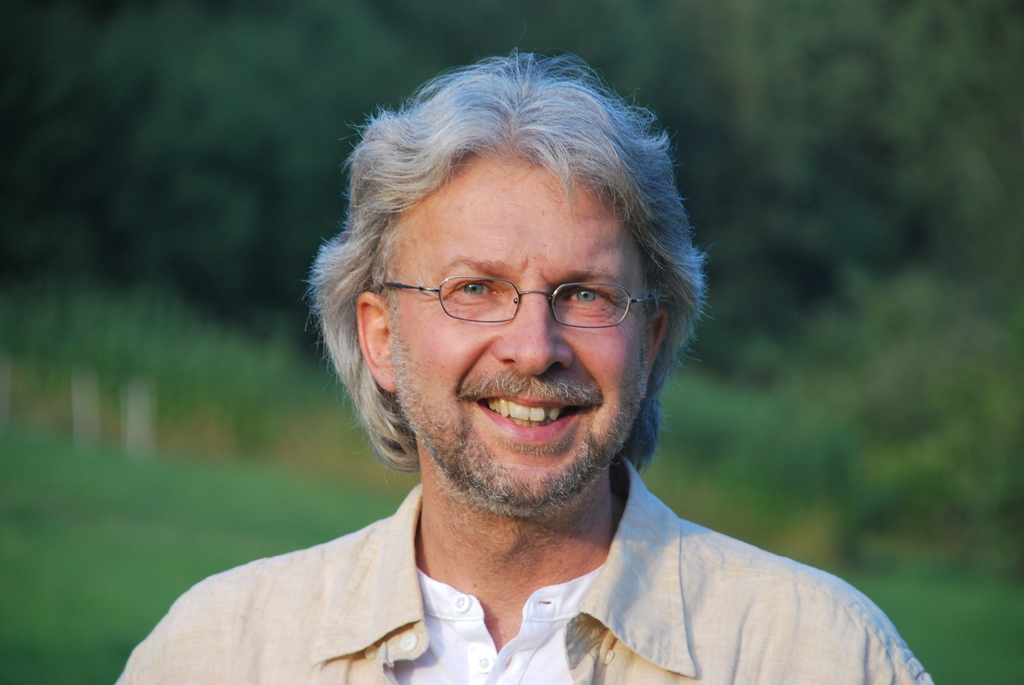 Gerhard Christ mit Brille, Portrait, im Hintergrund unscharfe grüne Landschaft